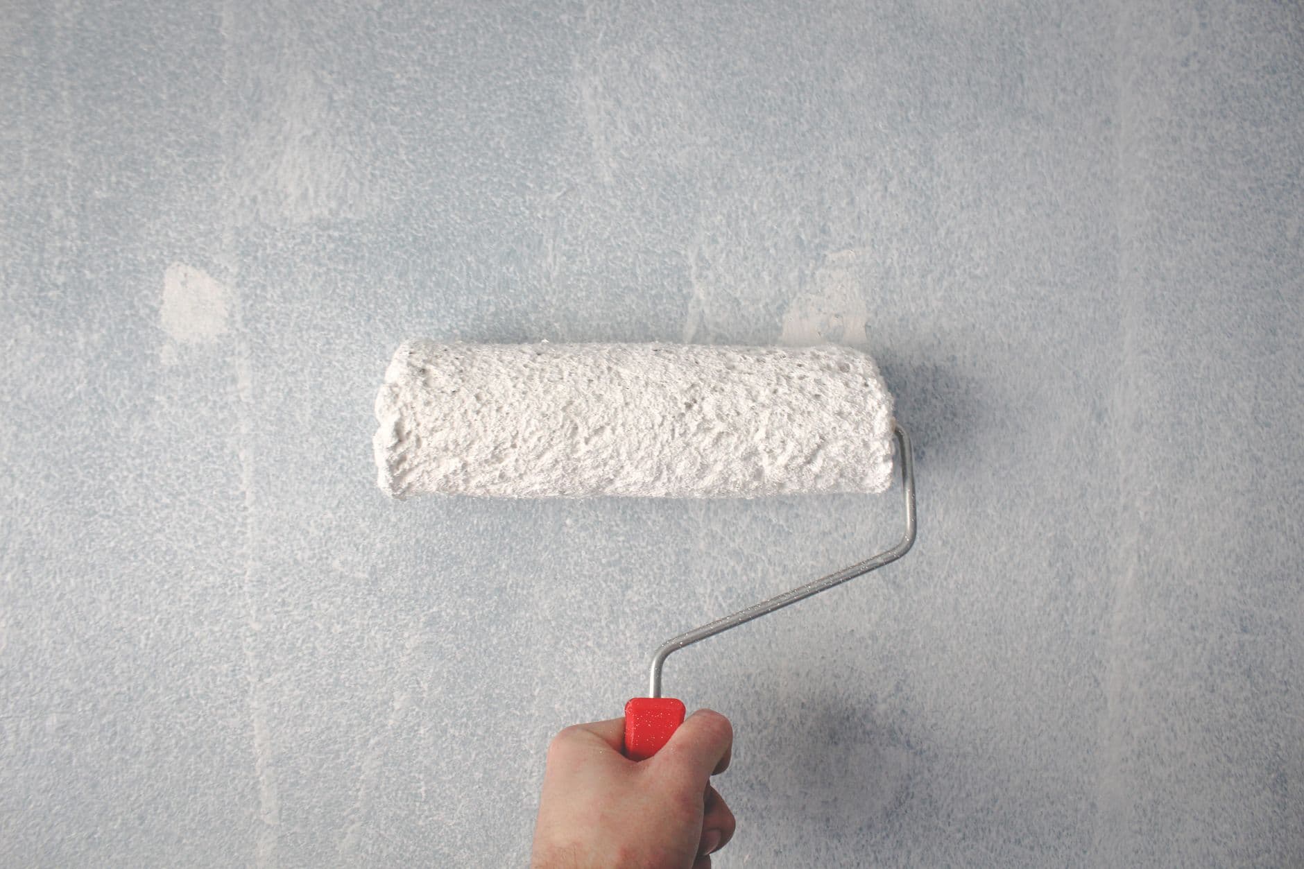 Pintor dando rodillo a la pared de una vivienda
